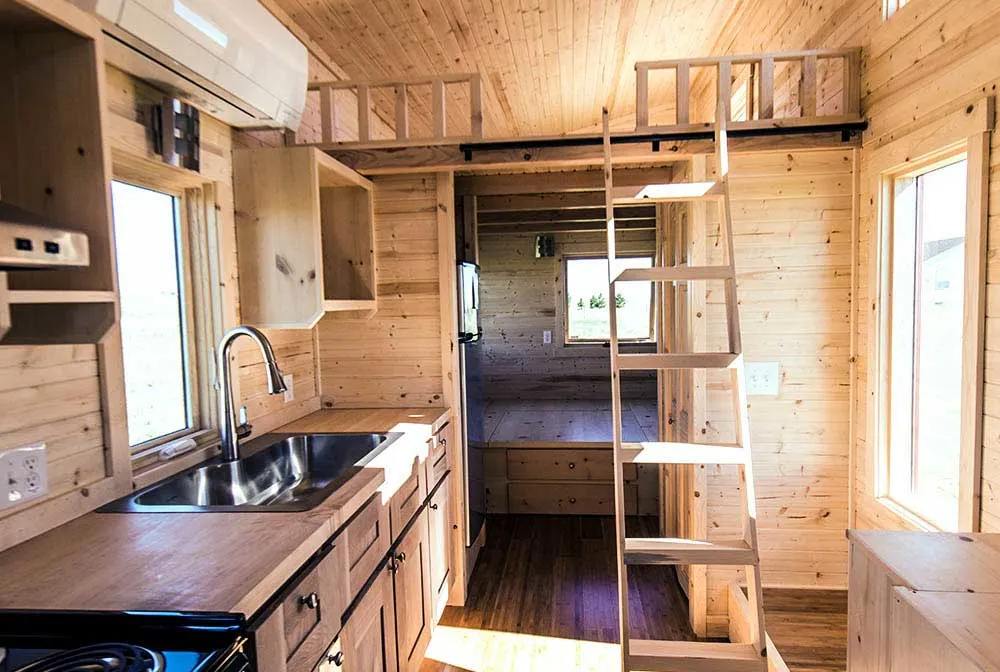 Large kitchen space leading into the downstairs bedroom - Roanoke by Tumbleweed Tiny House