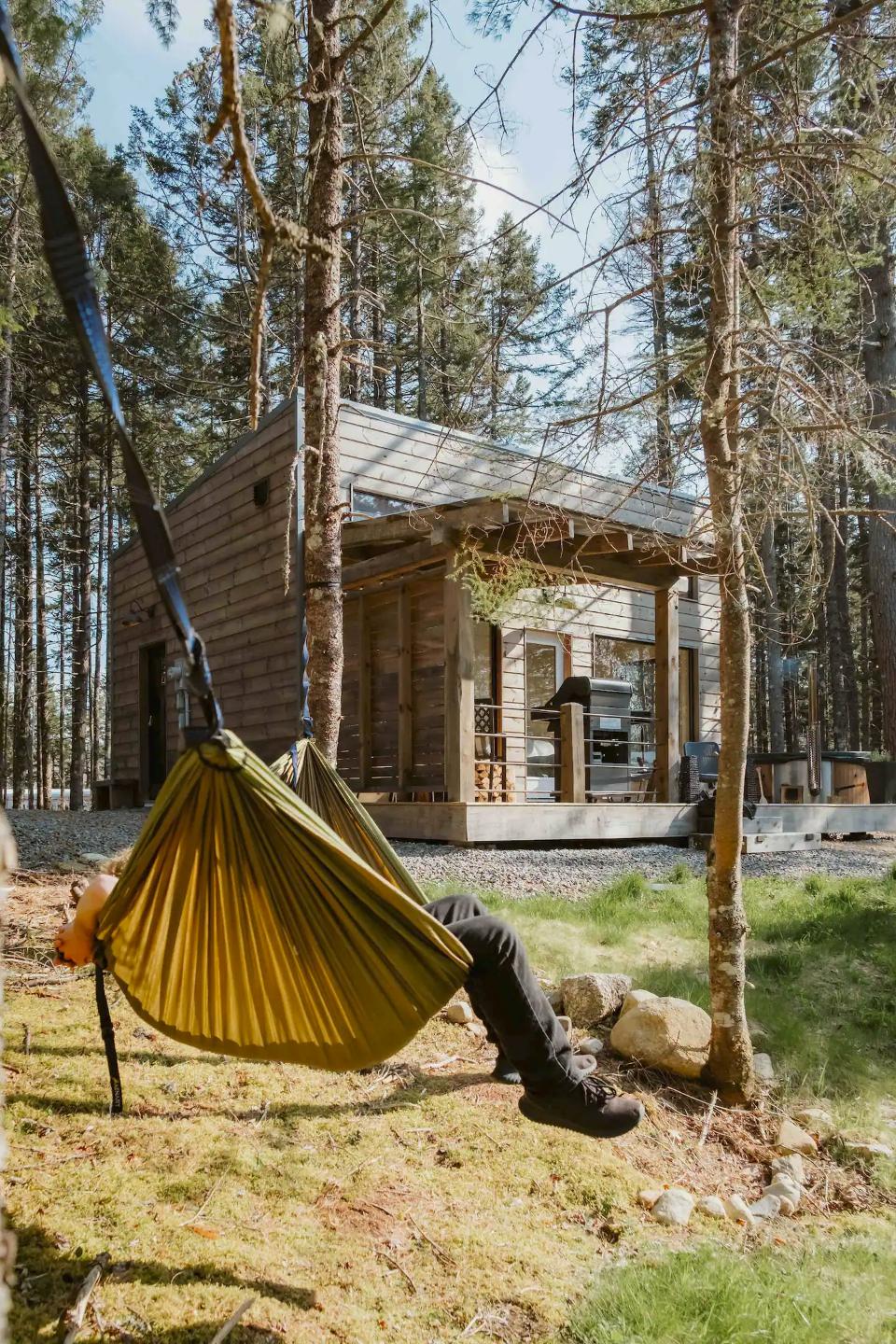 Person Relaxing in Hammock in Front of Tiny House - Chalet at Petite Rivière Bridge