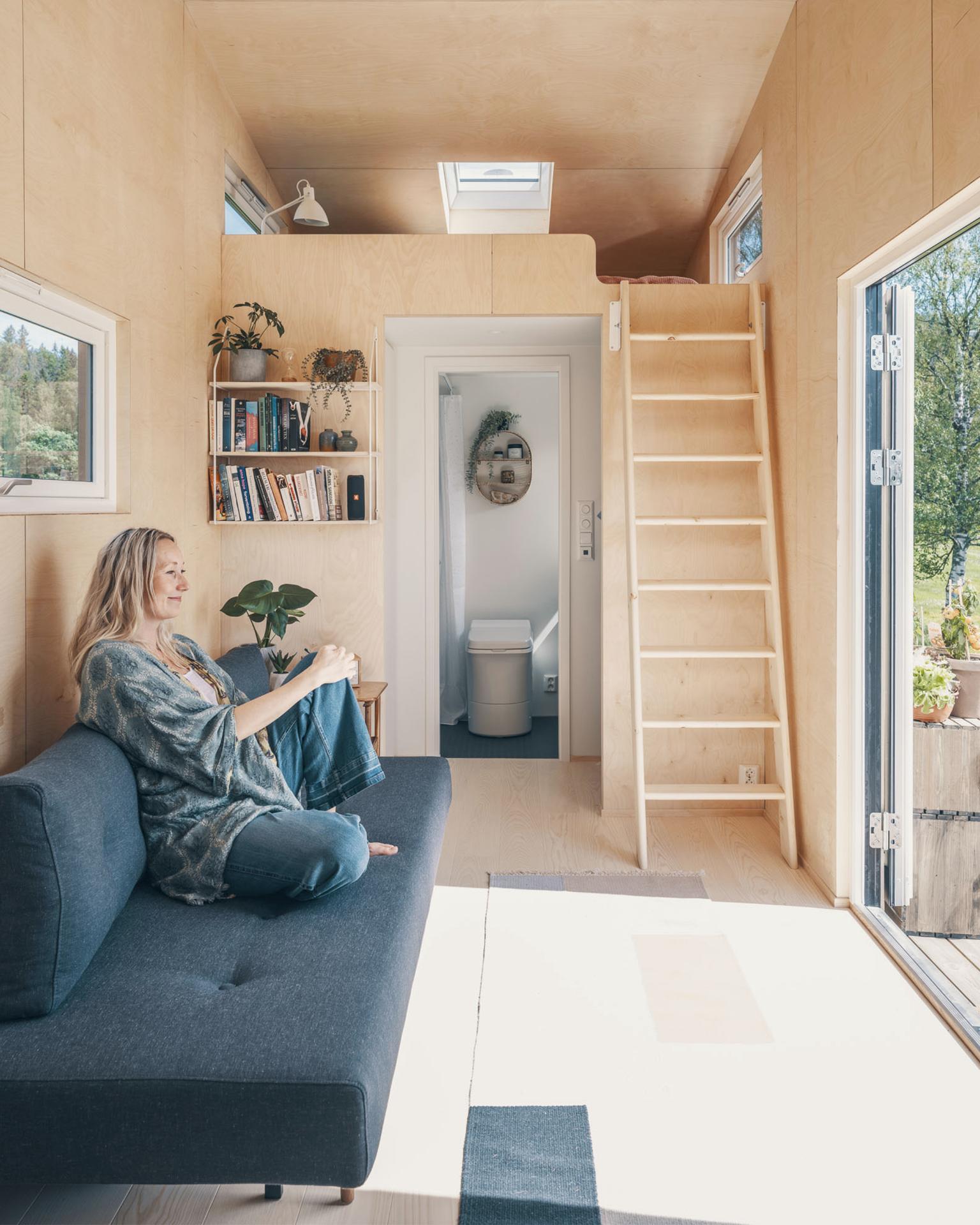 Woman Sitting On Couch Looking Out Doors - Tind by Norske Mikrohus