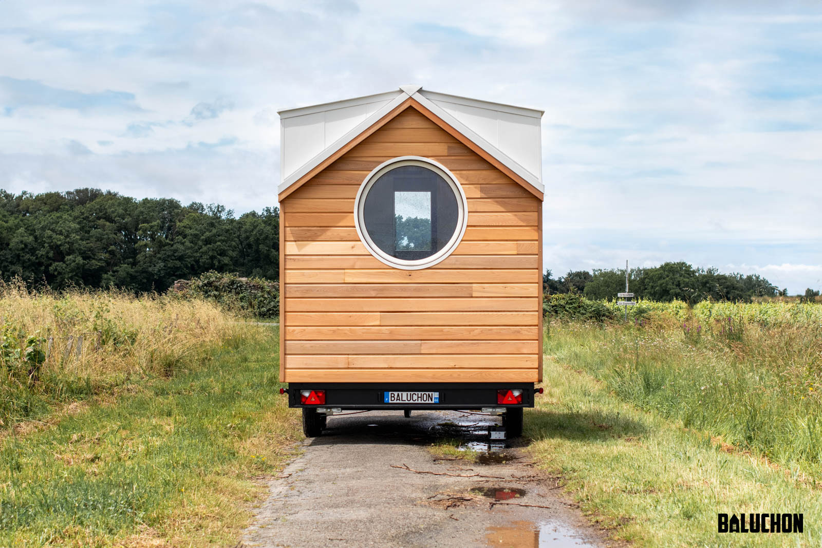 Exterior View with Natural Wood Siding and Circular Window - Nano Suisse by Baluchon