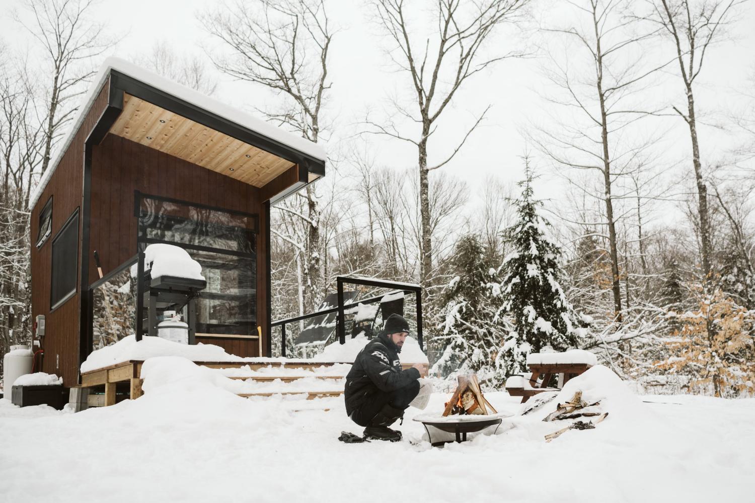 Snowscape of Tiny House with Man Squatting by Fire Pit - Sage by Cabinscape